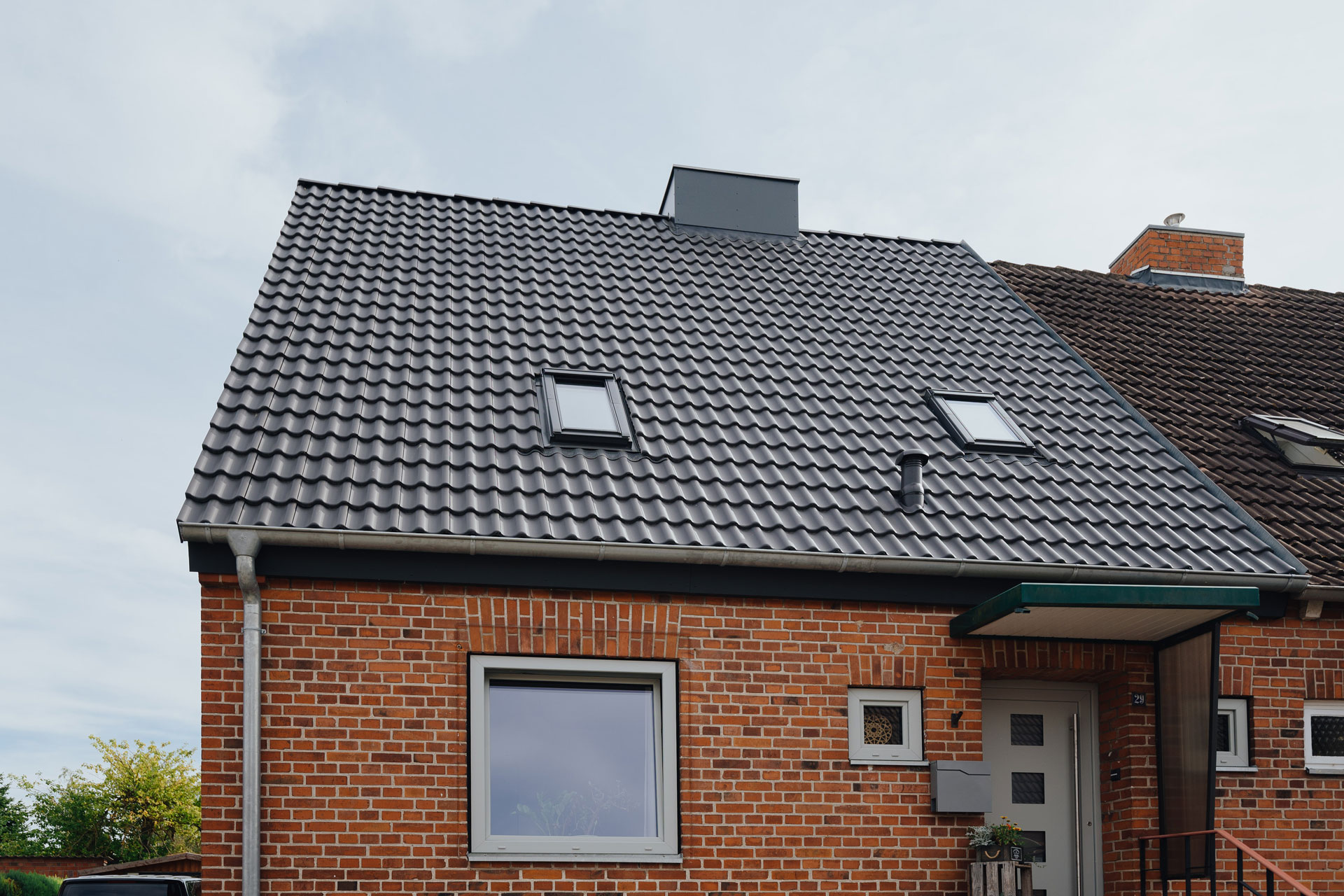 Schiefergraue Dachziegel glänzen in der Sonne.