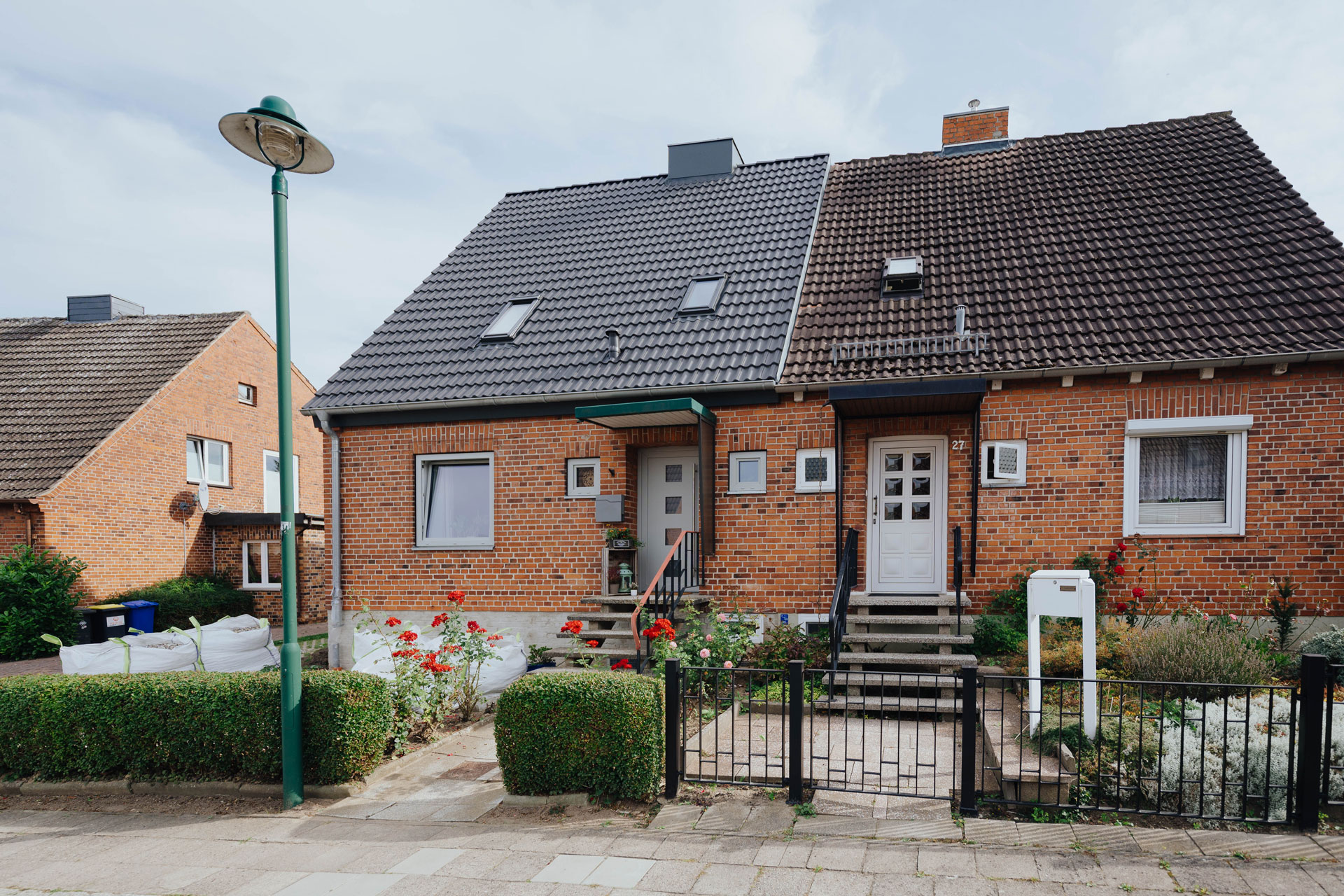Ein neugedecktes Dach eines Einfamilienhauses grenzt sich deutlich von dem angrenzenden Einfamilienhaus ab.